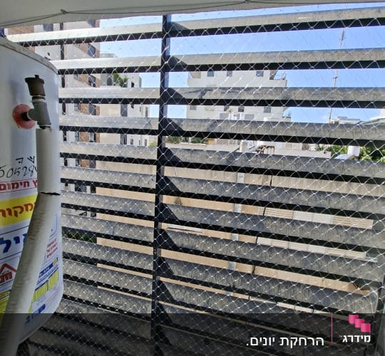 רשת יונים מותקנת על מרפסת עם נוף לבניינים